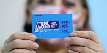 A person shows a vaccination card for the coronavirus disease COVID-19 at a vaccination centre in Santiago, on 10 January 2022. - Chile started administering today a fourth COVID-19 vaccine dose to people over the age of 12 with weakened immune systems. (Photo by Javier TORRES / AFP)