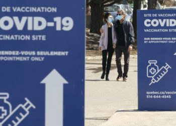 A couple leaves a COVID-19 vaccination clinic in Montreal, on Tuesday, March 23, 2021. THE CANADIAN PRESS/Paul Chiasson