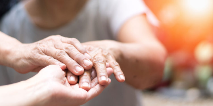 Geriatric doctor or geriatrician concept. Doctor physician hand on happy elderly senior patient to comfort in hospital examination room or hospice nursing home or wellbeing county.