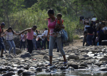 A woman carrying a child walks across the Tachira river on the outskirts of Cucuta, on the Colombian-Venezuelan border, Colombia February 25, 2019. REUTERS/Marco Bello