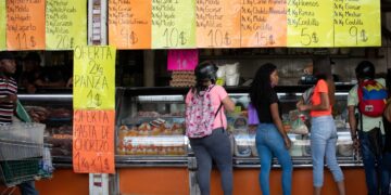 AME9701. CARACAS (VENEZUELA), 02/07/2021.- Varias personas compran en una carnicería el 25 de junio de 2021, en Caracas (Venezuela). Venezuela lleva inmersa en la pesadilla de la hiperinflación desde noviembre de 2017, una época de cifras mareantes que ha derivado en una dolarización espontánea como boya de salvación. Sin embargo, en los últimos meses, el incremento de los precios ha comenzado a frenarse, lo que alimenta la esperanza de dejar atrás el mal sueño. EFE/ Rayner Peña R